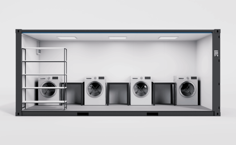 Vue de face intérieure d'un conteneur 20 pieds aménagé en laverie avec quatre machines à laver et étagères.